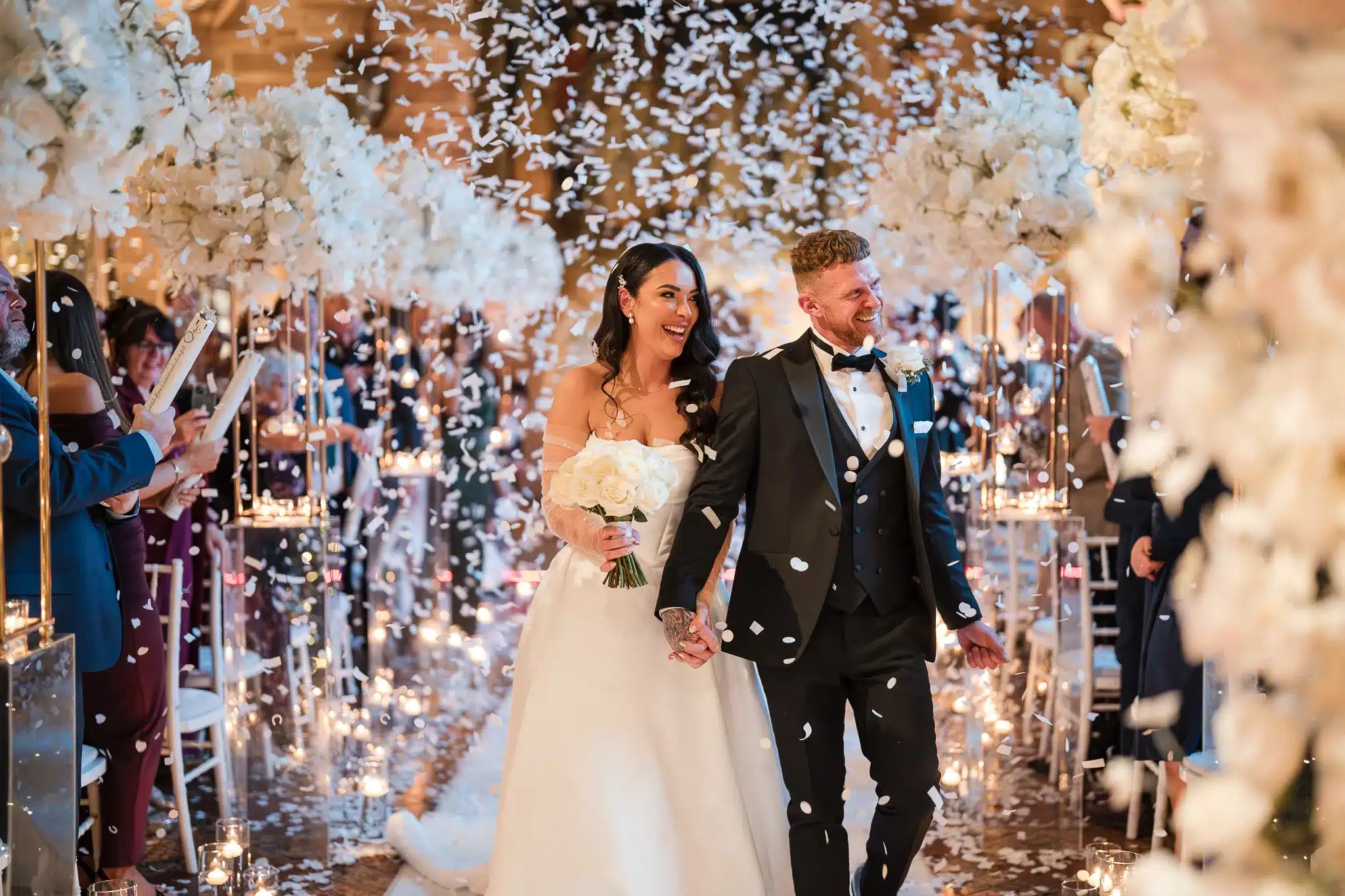 Transform your wedding day into a fairy tale with this stunning decor at Peckforton Castle. Designed by a Cheshire wedding stylist, the ceremony setup features cascading white florals, glowing candles, and delicate lighting, creating an atmosphere of timeless romance and sophistication.